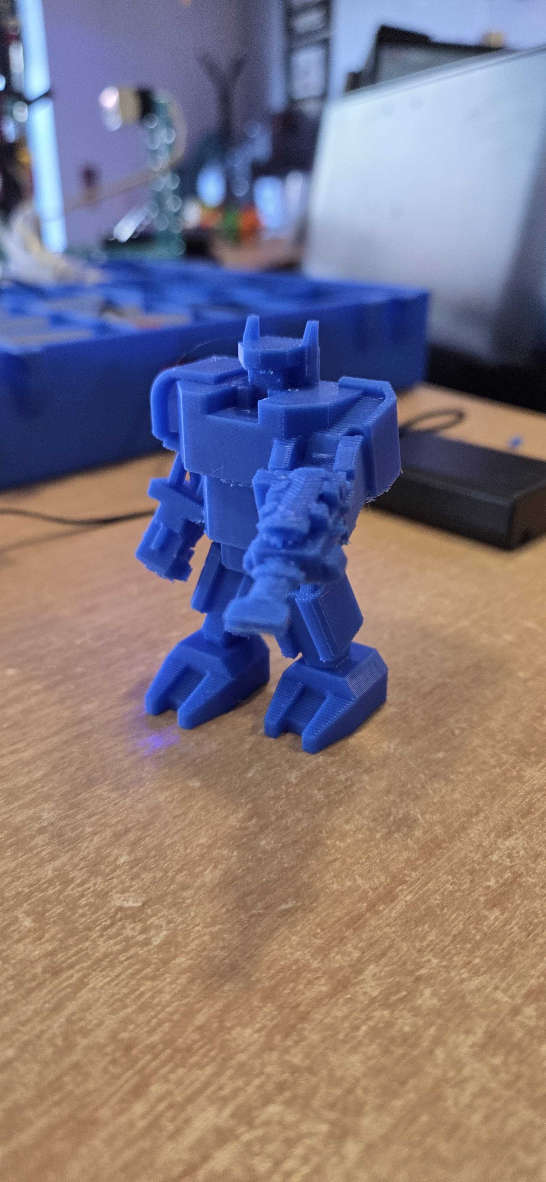 A detailed 3D printed robot figure created at Player Ready. This blue miniature mech showcases excellent detail work with distinctive features including shoulder-mounted components, articulated limbs, and a characterful stance.