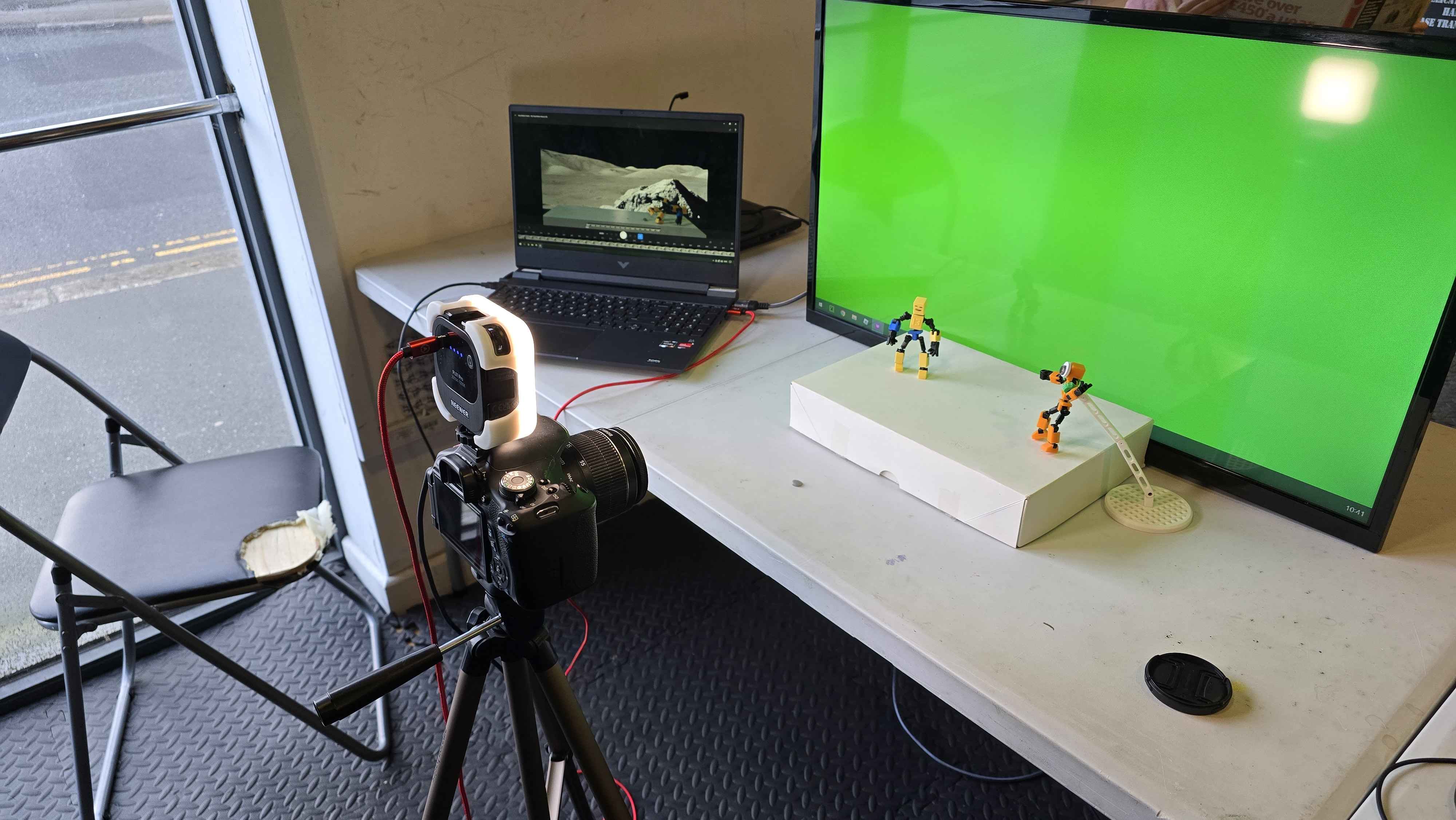 Stop-motion animation setup in progress! Using a green screen, LEGO figures, and professional camera equipment to create animated content. The laptop shows editing software where the magic comes together frame by frame.